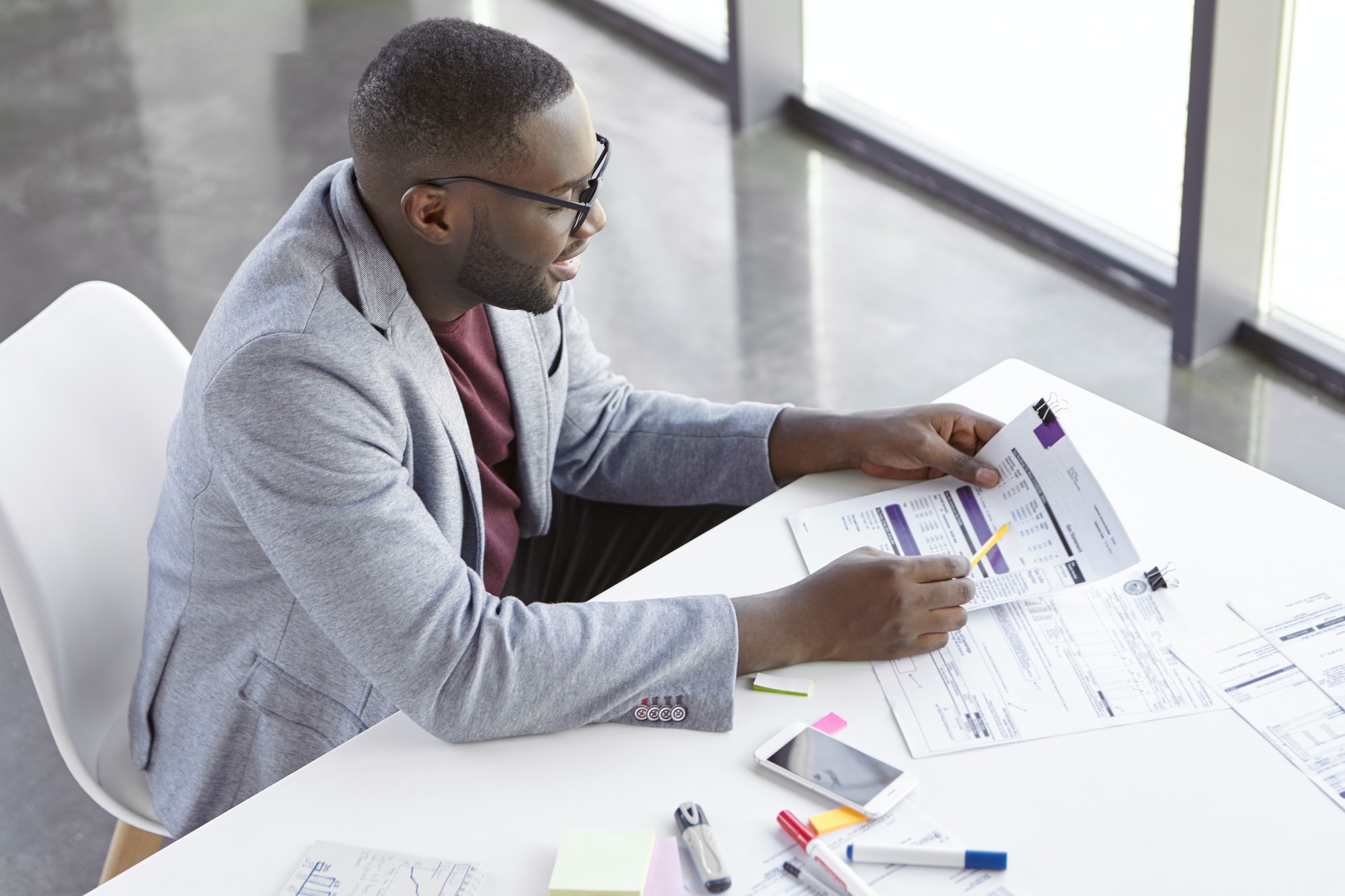 top-view-of-dark-skinned-african-male-copywriter-or-enterpreneur-looks-attentively-at-documents-stu.jpg